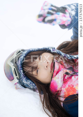 スキーウェアを着てゲレンデで雪と戯れる若い女性 スキーウェアを着てゲレンデで雪と戯れる若い女性 137376913