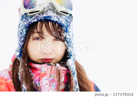 スキーウェアを着てゲレンデで雪と戯れる若い女性 137376928