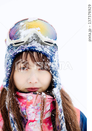 スキーウェアを着てゲレンデで雪と戯れる若い女性 137376929