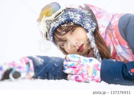 スキーウェアを着てゲレンデで雪と戯れる若い女性 スキーウェアを着てゲレンデで雪と戯れる若い女性 137376931
