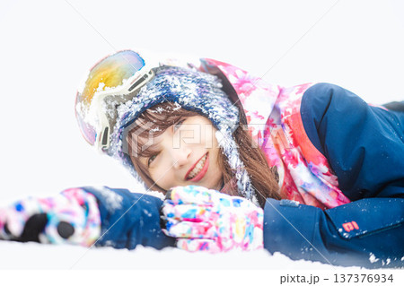 スキーウェアを着てゲレンデで雪と戯れる若い女性 137376934