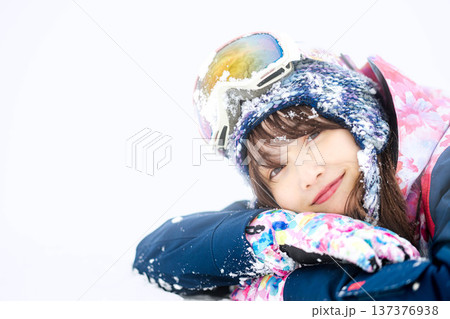 スキーウェアを着てゲレンデで雪と戯れる若い女性 137376938
