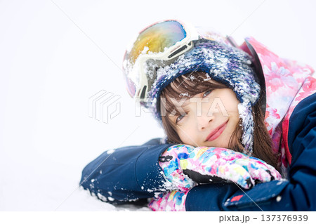 スキーウェアを着てゲレンデで雪と戯れる若い女性 137376939