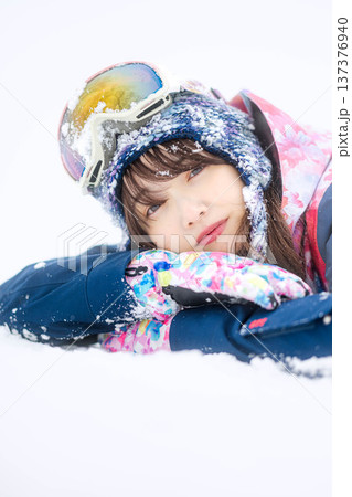 スキーウェアを着てゲレンデで雪と戯れる若い女性 137376940