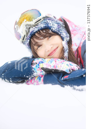 スキーウェアを着てゲレンデで雪と戯れる若い女性 137376941
