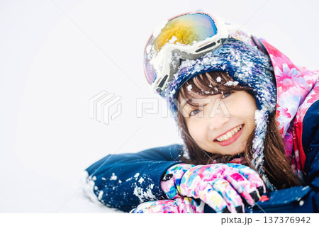スキーウェアを着てゲレンデで雪と戯れる若い女性 137376942
