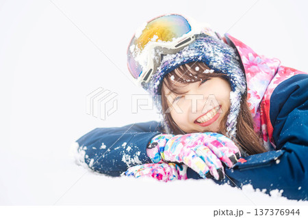 スキーウェアを着てゲレンデで雪と戯れる若い女性 スキーウェアを着てゲレンデで雪と戯れる若い女性 137376944