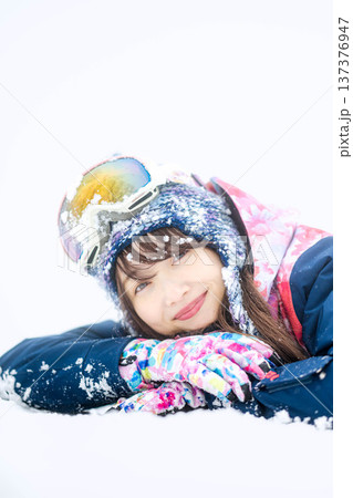 スキーウェアを着てゲレンデで雪と戯れる若い女性 137376947