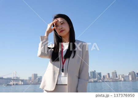 まぶしい日差しをさえぎる若いビジネスウーマン まぶしい日差しをさえぎる若いビジネスウーマン 137376950