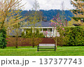 Bench in a park in front of residential house on overcast spring day 137377743