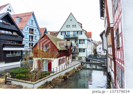 A tranquil canal in the fishermans quarter of Ulm, Germany. Reflections of colorful buildings line the water edge, creating a serene urban scene. 137379034
