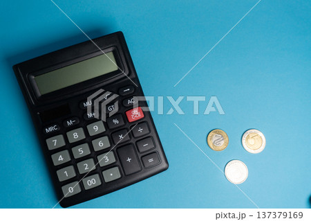 Calculator and coins on a blue background showing financial activity and basic math work Calculator and coins on a blue background showing financial activity and basic math work 137379169