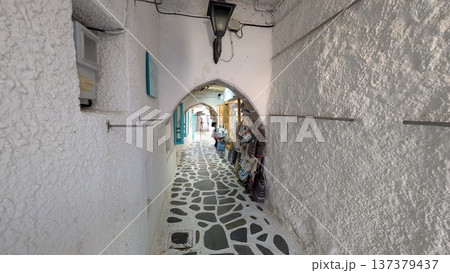 Cobblestone narrow shopping street under the arches surrounded by white walls Cobblestone narrow shopping street under the arches surrounded by white walls 137379437