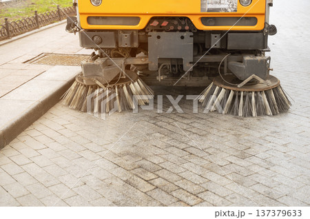 Modern street cleaning vehicle with rotating brushes working in an urban area Modern street cleaning vehicle with rotating brushes working in an urban area 137379633