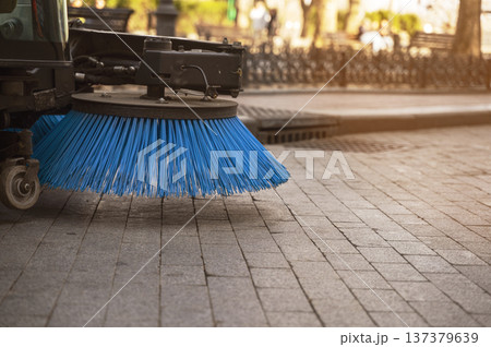 Blue synthetic bristles of a road cleaning machine part on a granite sidewalk. 137379639
