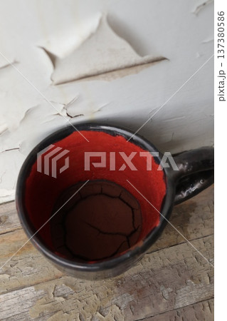 Red and black ceramic coffee cup with coffee grounds. 137380586