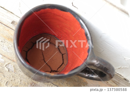 Red and black ceramic coffee cup with coffee grounds. 137380588