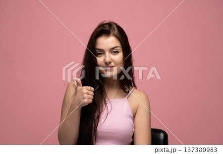 Young woman giving thumbs up gesture, expressing approval, satisfaction, and agreement with a positive attitude Young woman giving thumbs up gesture, expressing approval, satisfaction, and agreement with a positive attitude 137380983
