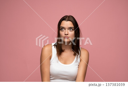 Young woman having an idea or feeling surprised, looking up and to the side on pink background Young woman having an idea or feeling surprised, looking up and to the side on pink background 137381039