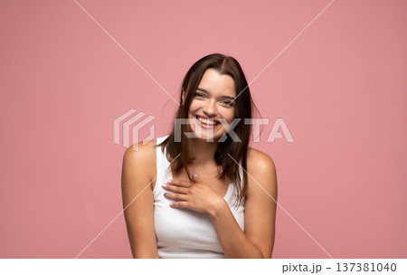 Young brunette woman laughing and expressing joy on a pink background, feeling positive and happy Young brunette woman laughing and expressing joy on a pink background, feeling positive and happy 137381040