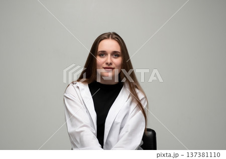 Young woman with long brown hair wearing a white shirt in a studio, looking at camera confidently Young woman with long brown hair wearing a white shirt in a studio, looking at camera confidently 137381110