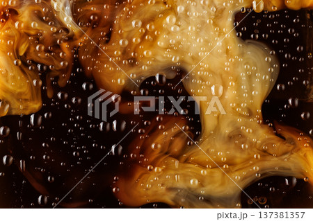 Macro shot of milk mixing into iced coffee with condensation Macro shot of milk mixing into iced coffee with condensation 137381357