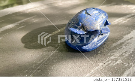 Ancient style blue scarab beetle carved from stone on a dark textured background. Egyptian souvenir. Ancient style blue scarab beetle carved from stone on a dark textured background. Egyptian souvenir. 137381518