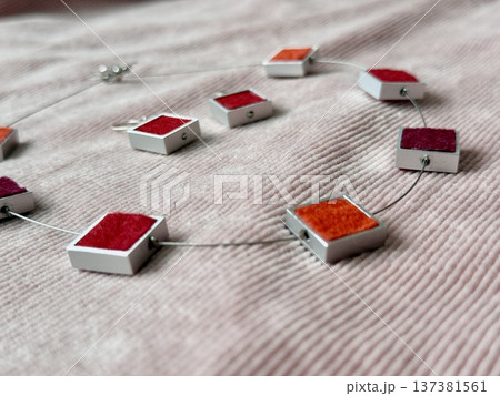Colorful geometric jewelry necklace with square pendant design on textured fabric background Colorful geometric jewelry necklace with square pendant design on textured fabric background 137381561