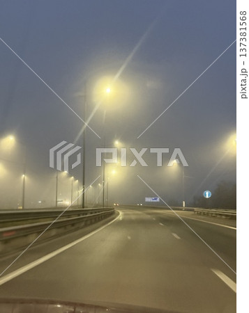 Misty night road with glowing streetlights and foggy atmosphere, ideal for background imagery 137381568