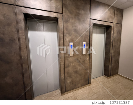 Elevator doors in modern lobby with metallic finishes and floor tiles Elevator doors in modern lobby with metallic finishes and floor tiles 137381587
