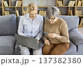 Senior woman paying online with help, credit card and laptop on sofa at home 137382380