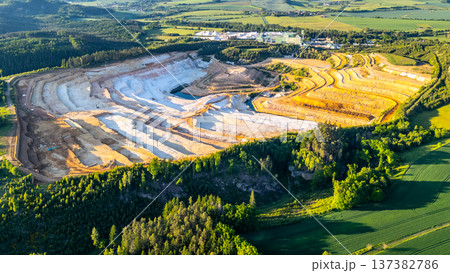 The image shows a large sandstone quarry located in Strelec, Czech Republic. The site is characterized by its layered landscape and surrounding fields. It is part of the Bohemian Paradise area. The image shows a large sandstone quarry located in Strelec, Czech Republic. The site is characterized by its layered landscape and surrounding fields. It is part of the Bohemian Paradise area. 137382786