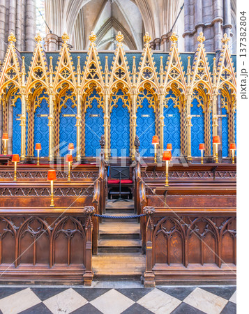 The Quire at Westminster Abbey shows wooden choir stalls arranged in rows. Stained glass and decorations enhance the historic space. Candles rest on the stalls, adding to the atmosphere. 137382804
