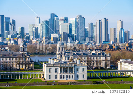 A stunning view from Greenwich Park shows historical buildings surrounded by lush greenery, contrasted with a skyline of modern skyscrapers in central London on a clear day. 137382810