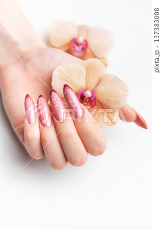 Woman's hand holding orchid showcasing beautiful manicure Woman's hand holding orchid showcasing beautiful manicure 137383008