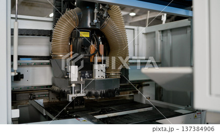 Industrial CNC milling machine with a spindle motor and dust extraction hose in a factory setting. 137384906
