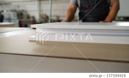 Close-up of white furniture panels on a workbench with a craftsman in a workshop Close-up of white furniture panels on a workbench with a craftsman in a workshop 137384928