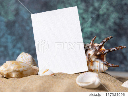 Mockup of blank vertical card on sand near seashells and blue ocean back, beach wedding stationery Mockup of blank vertical card on sand near seashells and blue ocean back, beach wedding stationery 137385096