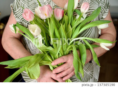 Unrecognizable woman in silver sequin dress holding a bouquet of pink tulips, 137385190