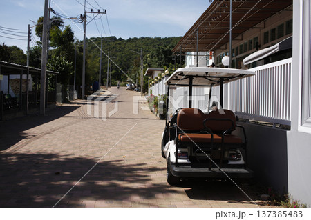 A golf cart is parked near a hotel on the island. A golf cart is parked near a hotel on the island. 137385483