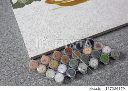 Paint set for painting by numbers. Pastel colors in small containers with numbers to help you understand which colors to use. Simple hobby involving painting areas on painting canvas Paint set for painting by numbers. Pastel colors in small containers with numbers to help you understand which colors to use. Simple hobby involving painting areas on painting canvas 137386179