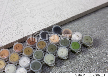 Colorful paint pots arranged neatly beside painting grid. Calm, creative atmosphere. Artistic process invites quiet focus and imagination. Ideal for tutorials, crafting blogs 137386181