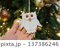 Christmas and New Year. Hand holding a white owl toy on the background of the Christmas tree 137386246