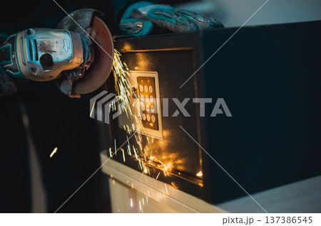 A man breaks into a safe with a grinder. A man breaks into a safe with a grinder. 137386545