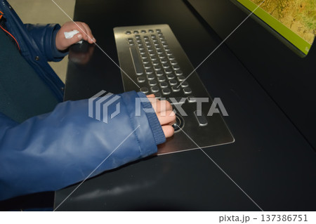 A close-up of a child's hands using an adaptive computer keyboard with large keys and a trackball. Concept: rehabilitation tools and educational support for children with disabilities. 137386751
