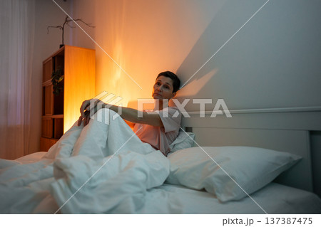 Exhausted pondering senior woman with insomnia sleep disorder sitting in bed with tired expression. 137387475