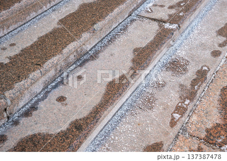 Deicing chemicals on stairs in winter. Technical salt grains on stone steps in cold season Deicing chemicals on stairs in winter. Technical salt grains on stone steps in cold season 137387478