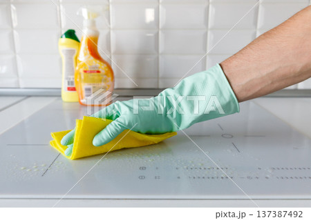 man hand in rubber gloves washing or cleaning induction hob 137387492