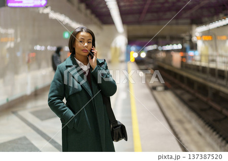 Serious african businesswoman talk on phone call at subway platform while waiting for metro train 137387520