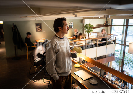 Thoughtful relaxed businessman drinking coffee at co-working, spending free time in lively city cafe 137387596